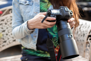 Fototapeta premium Close-up of female hands holding a professional camera. Female photographer with a professional camera.