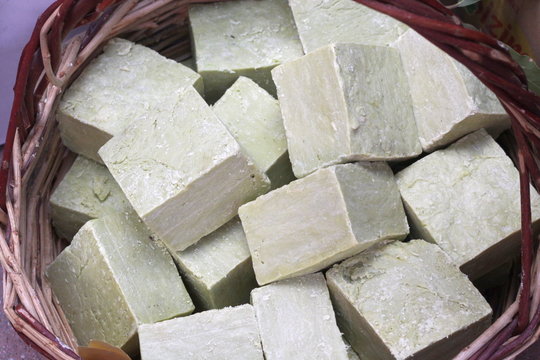 A pile of bars of natural olive soap in a wicker basket © Valentina