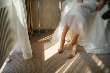Fototapeta na wymiar Bride wearing wedding shoes. Art lighting and wedding day