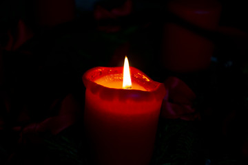 lonely red candle with small flame and dark background