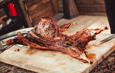 Whole grilled lamb on cutting board. Hot Meat dishes