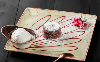 Chocolate cake or fondant with raspberries and vanilla ice cream ball on plate, sweet food