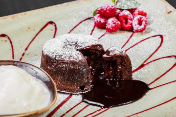 Chocolate cake or fondant with raspberries and vanilla ice cream ball on plate, sweet food
