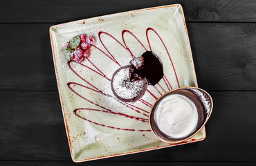 Chocolate cake or fondant with raspberries and vanilla ice cream ball on plate, sweet food