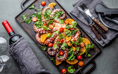 Whole octopus salad with orange, tomatoes and cress salad served on board with wine