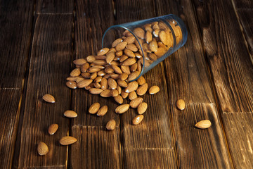 Almonds in tilted transparent blue glass on a wooden background