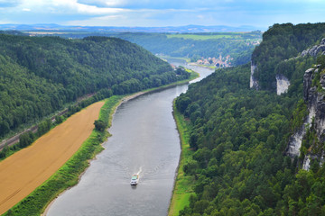 Fototapeta premium Panoramic view of Saxon Switzerland from the summits of Bastei Park. The river Elbe, ship, greenery and hills. Bad Shandau, Germany.