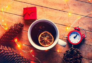 Cup of tea and Christmas box gift with alarm clock and Fairy Lights on wooden background