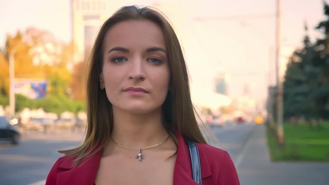 Young attractive female closeup looking on the camera standing on the street, city, expressing rebuke with her eyes