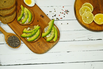 Toast with avocado on a wooden plate and white background