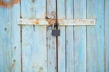 The background with old colored in blue wooden gate with lock