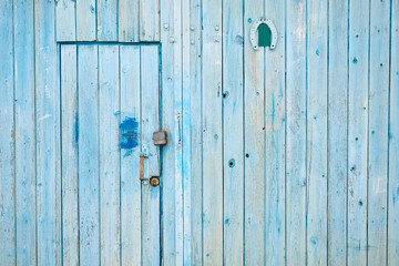 A textured blue wooden wall with locked door and horseshoe