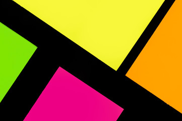 Green, yellow, orange and purple hue colorful office stickers on black paper. Office noteparer as...