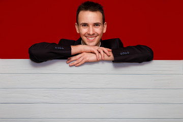 Young smiling man with blank red sign board. Handsome businessman holding banner with  copyspace for advertising messages, posters and text