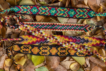 Five handmade homemade colorful natural woven bracelets of friendship in autumn dry leaves