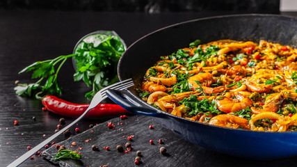 The concept of Spanish cuisine. Paella with seafood, shrimps, squid and greens, cooked in a wok pan...