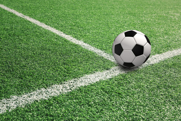 Fototapeta na wymiar Sunny football ball on soccer field with white lines.