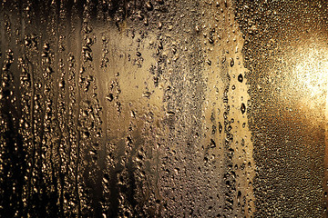 Drops of water on the glass, closeup. Golden abstract background. Beautiful texture. Background image for design.