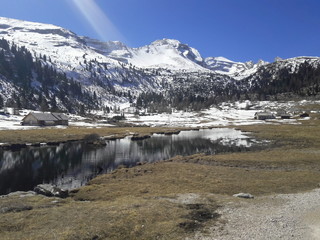 vallata alpi dolomiti con lago prato e montagne con neve sullo sfondo