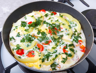Traditional rustic omelette with bacon, pasta and greens on  old black frying pan on background of vintage  table.