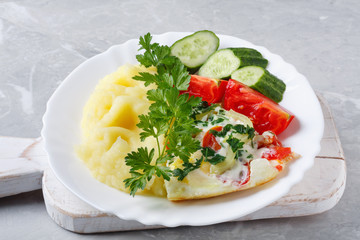 Hot tasty mashed potatoes with scrambled eggs, tomatoes, cucumbers and fresh parsley
