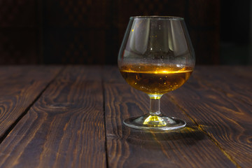 Glass of whiskey or brandy on wooden table