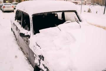 a car's front part buried in snow after a blizzard. Car covered with snow after big snowstorm.