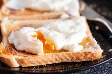 A close-up of imperfect homemade poached eggs on white toast