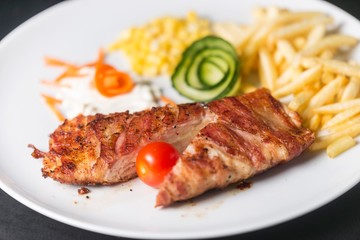 chicken meat with bacon. chicken meat with french fries and corn. fast food meal on black background. 