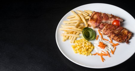 chicken meat with bacon. chicken meat with french fries and corn. fast food meal on black background. 