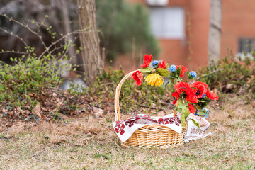 Russian Orthodox Easter blessing wicker straw basket with nobody on grass ground outside at church, flowers