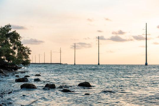 Sunset in Islamorada, Florida Keys, with sky, power lines, water on gulf of Mexico, or Atlantic Ocean, horizon, island, rocks, coast shore