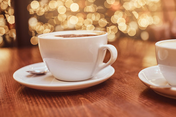 Hot coffee with art in a cup on the wooden table in a coffee shop, blur background with bokeh effect