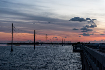 Obraz premium Sunrise in Islamorada, Florida Keys, with red orange sky, overseas highway road, in Atlantic Ocean, gulf of Mexico, horizon, power lines