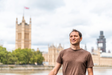 Fototapeta premium London, UK happy smiling young man face and cityscape skyline of city with Thames River, Westminster during cloudy day on Albert Embankment