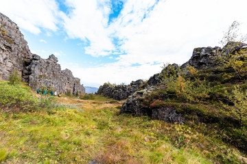 Thingvellir National Park grass autumn plants during day landscape, people walking on canyon trail in Iceland, Golden circle route