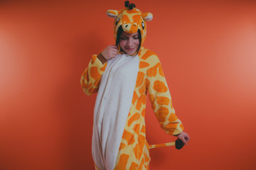 pajamas in the form of a giraffe. emotional portrait of a girl on an orange background. crazy and...