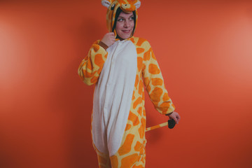pajamas in the form of a giraffe. emotional portrait of a girl on an orange background. crazy and...