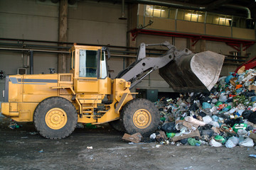 Bulldozer move pile of waste in a landfill.
