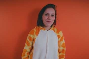 pajamas in the form of a giraffe. emotional portrait of a girl on an orange background. crazy and...