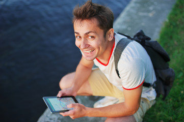 Side view of male blogger browsing profile in networks on smartphone via 4G internet connection with modern tablet. Young man chatting online on mobile phone