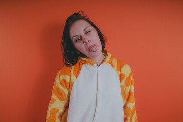 pajamas in the form of a giraffe. emotional portrait of a girl on an orange background. crazy and...