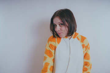 pajamas in the form of a giraffe. emotional portrait of a girls on an orange background. crazy and...