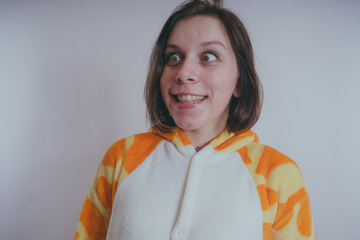 pajamas in the form of a giraffe. emotional portrait of a girls on an orange background. crazy and...