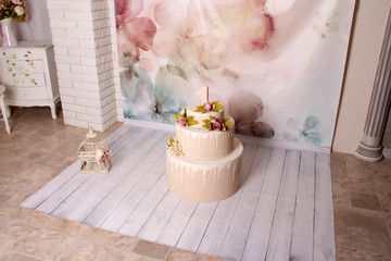 decor with cake for a photoshoot. a cage with a birdie on a pink background with flowers.