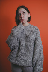 Young girl in warm grey sweater posing on orange background, woman with short haircut in knitted...