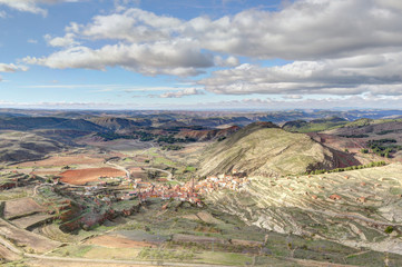 A landscape of the small rural town of Monterde, in the Aragon countryside, among hills and pastures, in a sunny autumn with clouds, in Spain