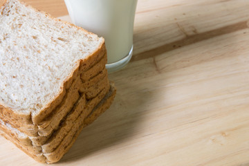 A Glass milk with bread slice on wood background