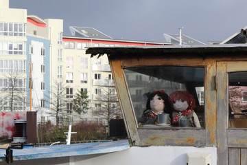 Two smiling rag dolls in a boat wooden cabin in the Avon wharf, during a cloudy winter day, in...