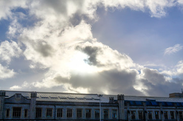 A blue sky with sun in backlight with clouds just after a storm, over an industrial factory in Friary, Bristol, United Kingdom